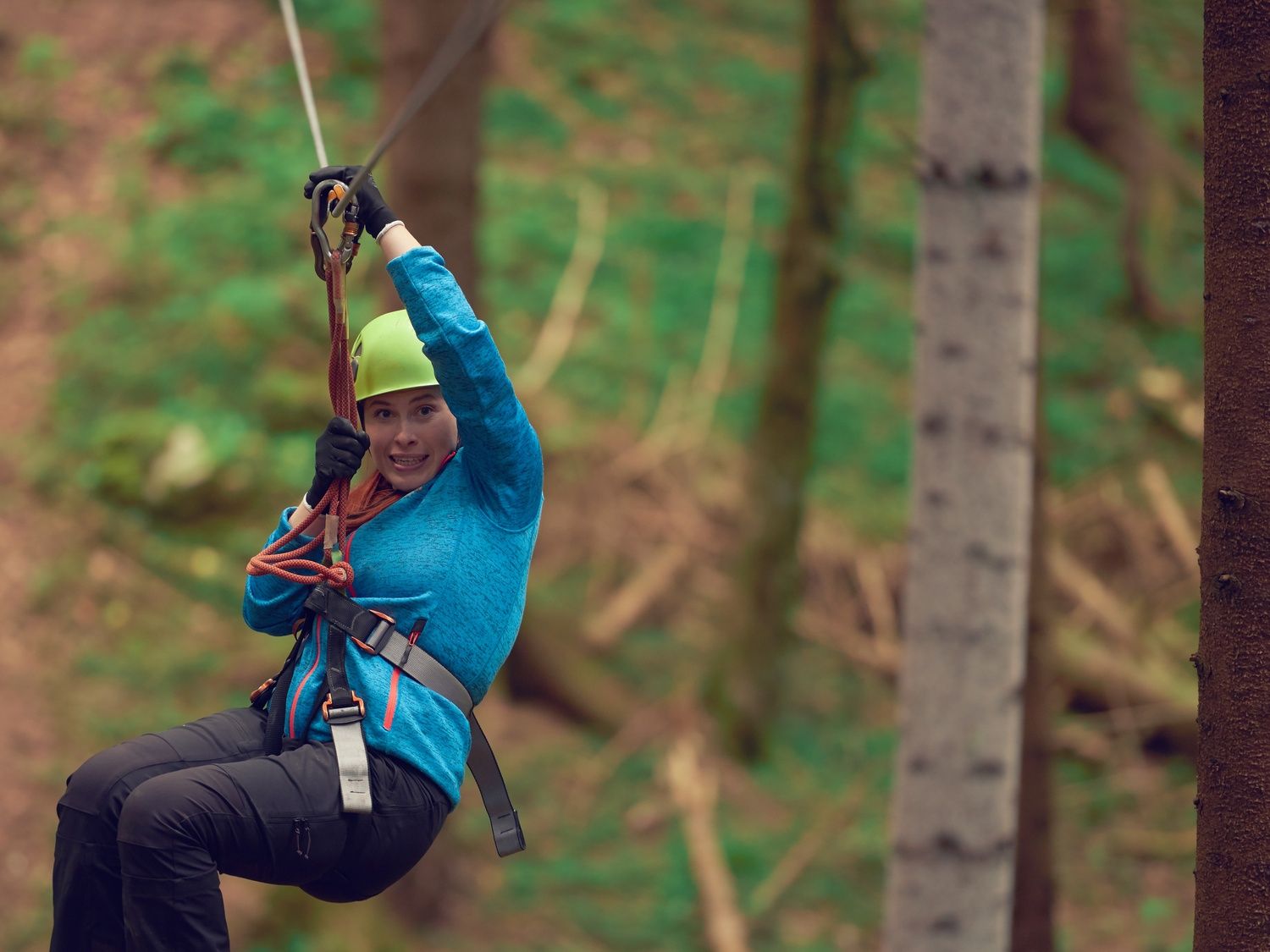 Lady on zipline through forest